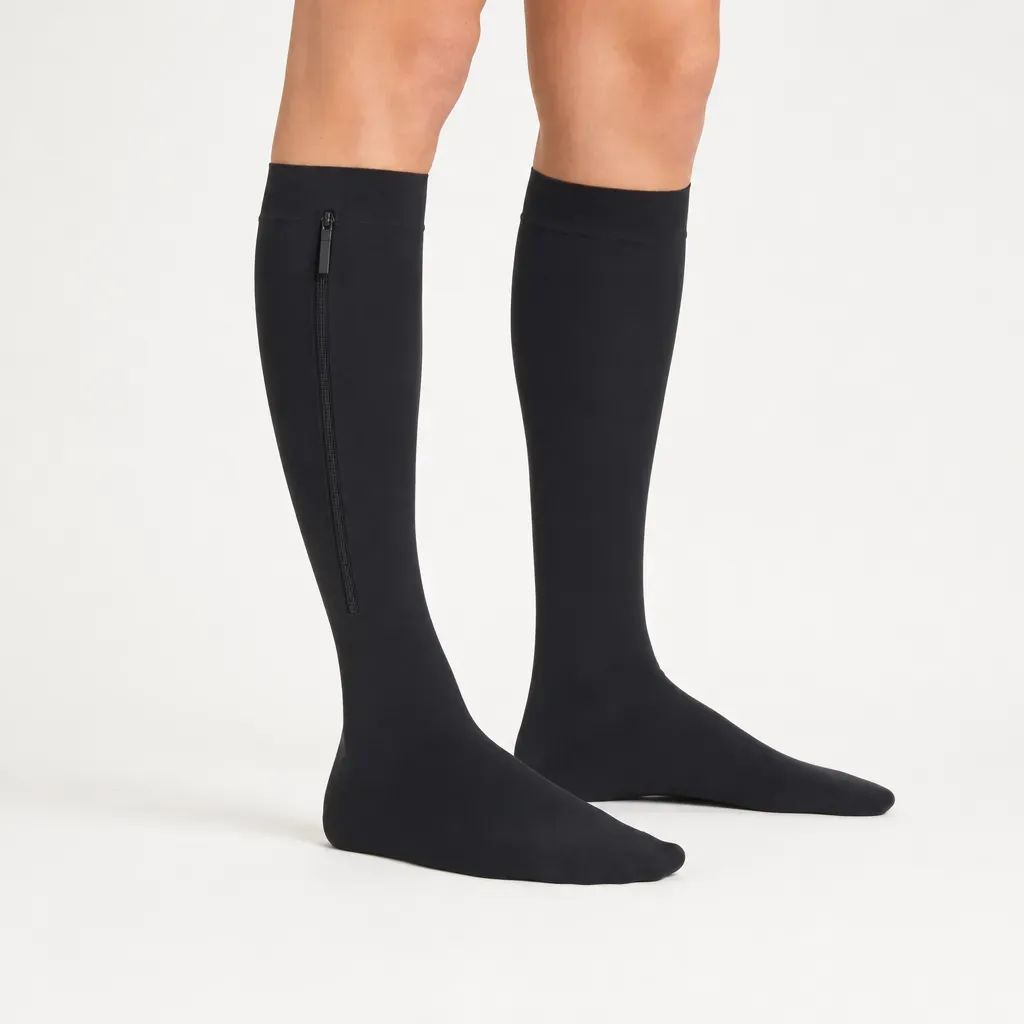 Lower legs in black closed-toe zipper compression socks, zipper on the outer side